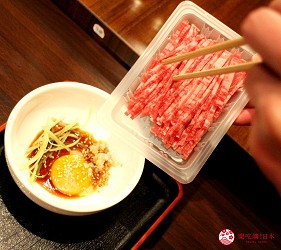 東京高田馬場燒肉激戰區的A5黑毛和牛絕品美味「吟まるJr.」的生拌牛肉「肉膾」(ユッケ)實際將生牛肉放進蛋黃拌醬中
